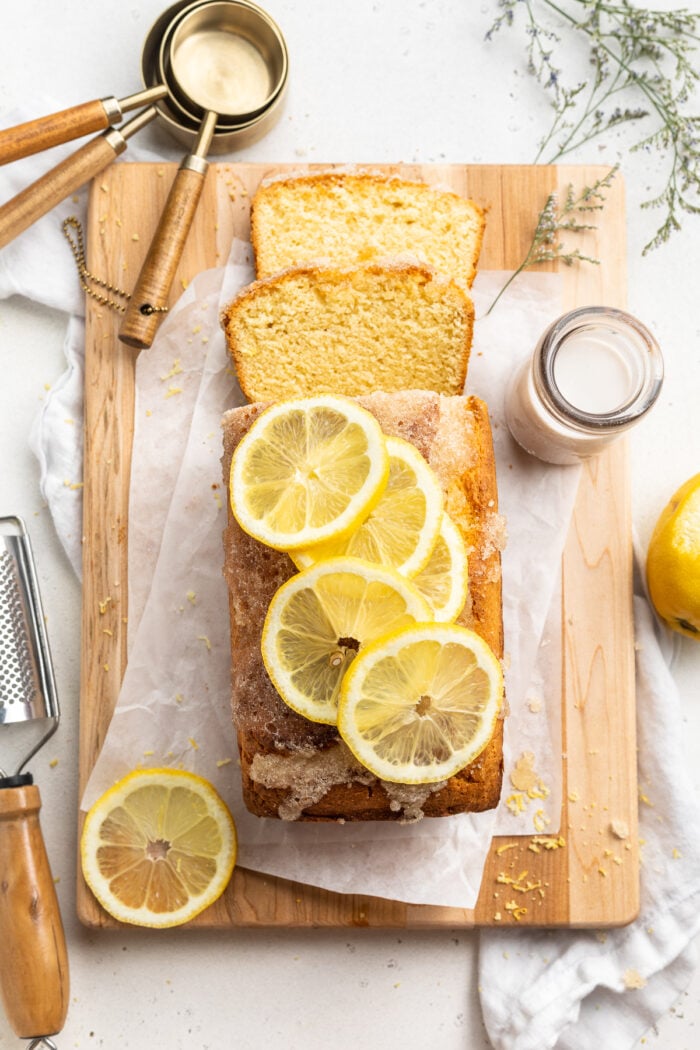 Overhead view of a gluten free lemon drizzle cake topped with slices of lemon.