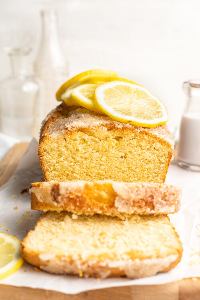 End-view of a gluten free lemon drizzle cake with two slices of cake cut off to show top of cake.