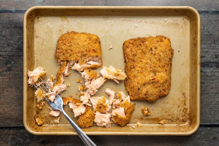Overhead view of baked, flaked, breaded salmon fillets on a baking sheet.