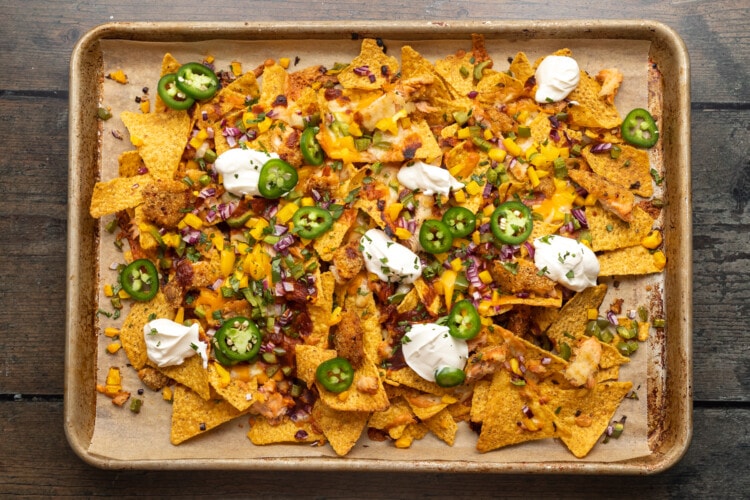 Overhead view of fully loaded honey chipotle salmon bbq nachos on a baking sheet.