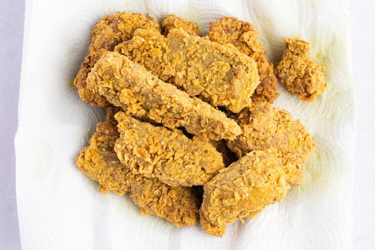Overhead view of seitan fried "chicken" tenders on a paper towel lined plate.
