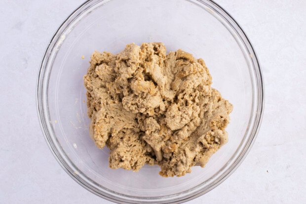 Overhead view of seitan fried "chicken" dough in large glass mixing bowl on white surface.