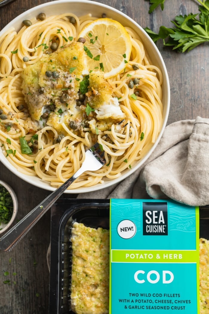 Overhead view of a bowl of cod piccata next to a package of potato-crusted cod fillets.