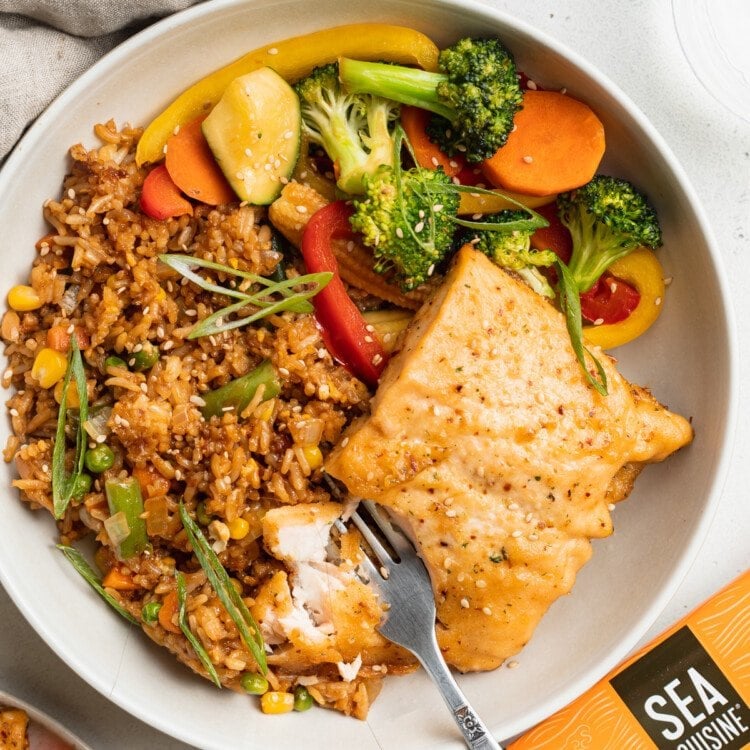 Overhead view of a teriyaki salmon hibachi dinner with fried rice and sauteed vegetables.