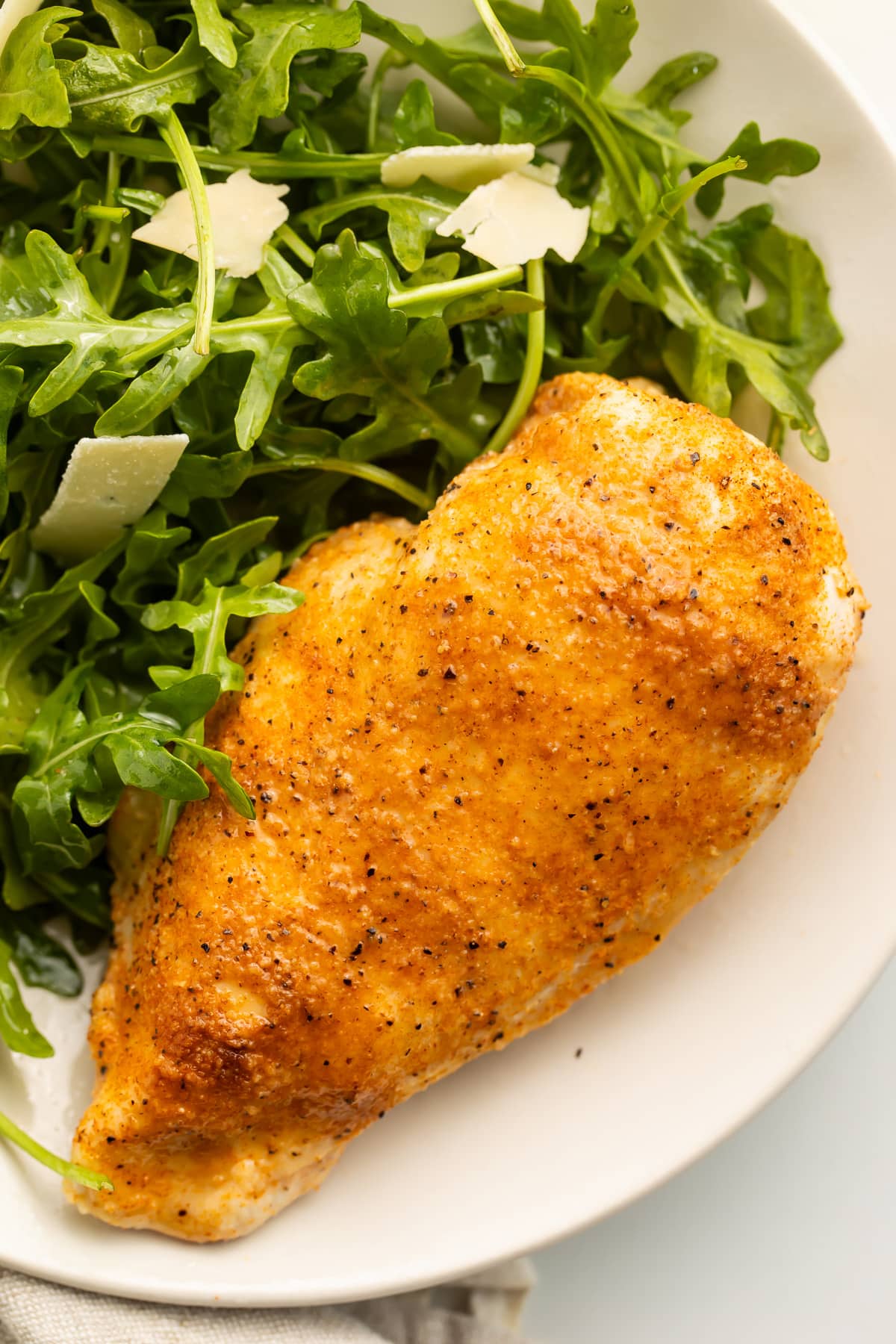 A whole Instant Pot chicken breast, fully cooked and resting on a plate with a small salad.
