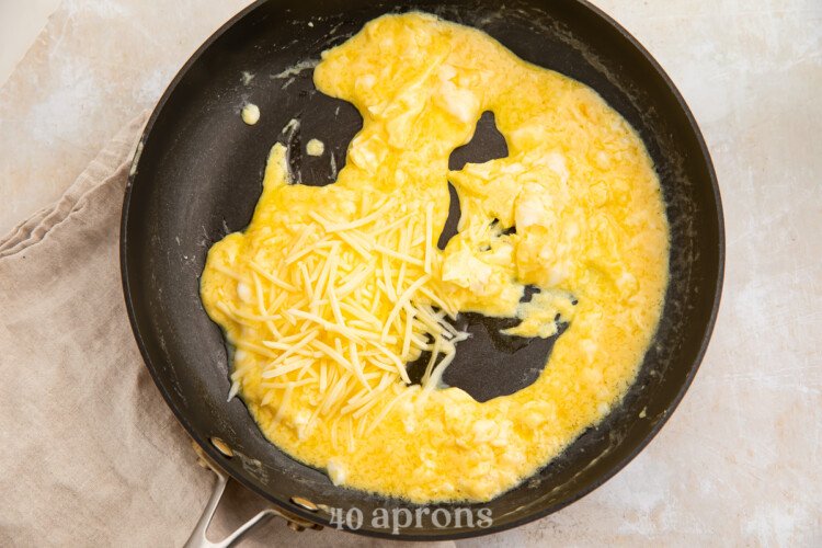 Overhead view of scrambled eggs in medium cast iron skillet.