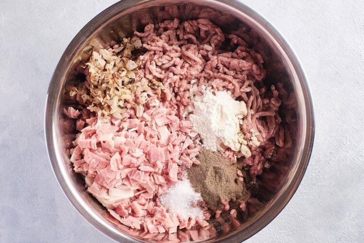 Overhead view of ingredients for Whole30 burgers in a large silver mixing bowl.