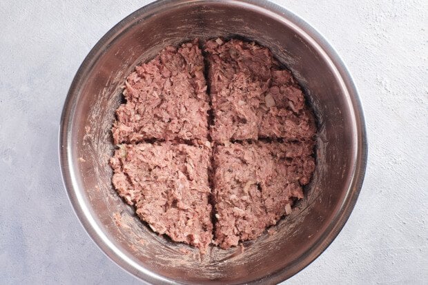 Overhead view of mixed Whole30 burger ingredients in a large silver bowl, divided into 4 sections.