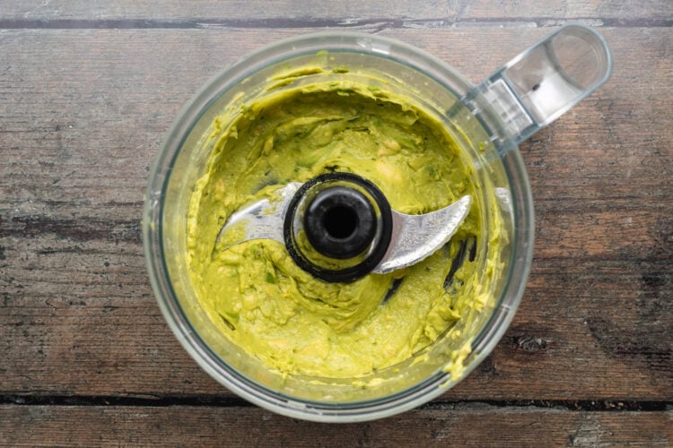 Overhead view of guacamole in a food processor bowl.