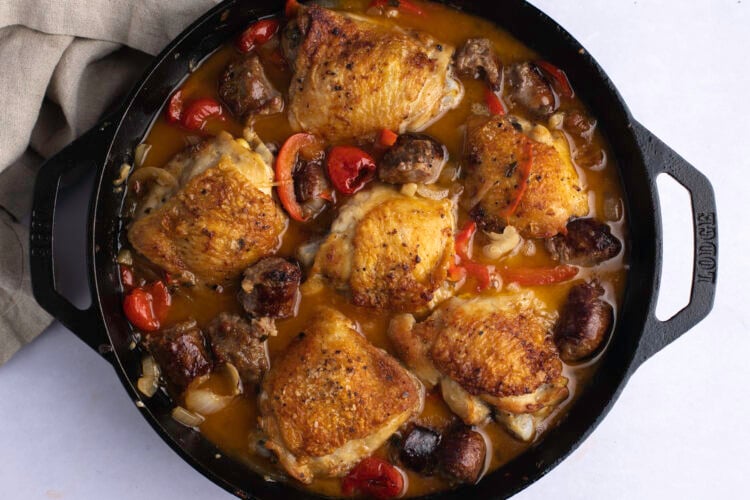 Overhead view of chicken scarpariello in a large cast iron skillet.