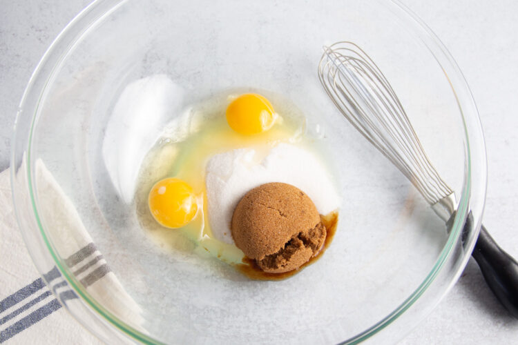 2 large eggs, brown sugar, and white sugar in large glass mixing bowl with whisk.