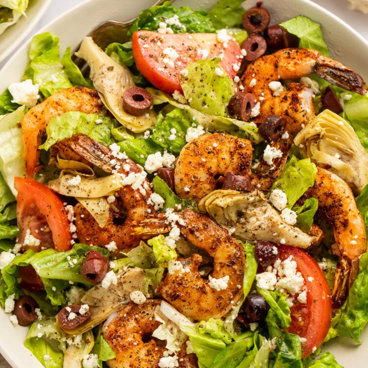 Close-up of blackened shrimp salad with tomatoes, olives, and feta.