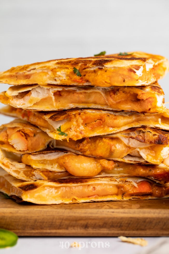Side view of chicken tikka masala quesadillas stacked on top of each other, resting on a cutting board.