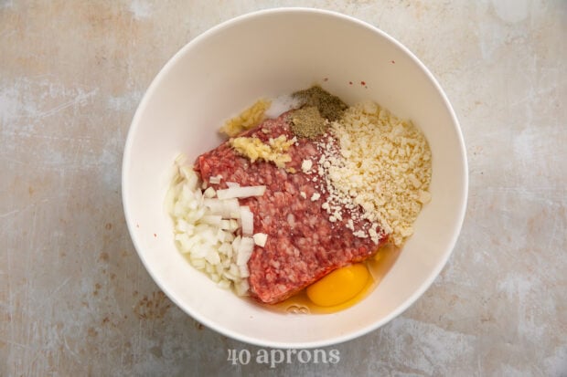 Overhead view of ingredients for gyro bowl meatballs in a large white mixing bowl.
