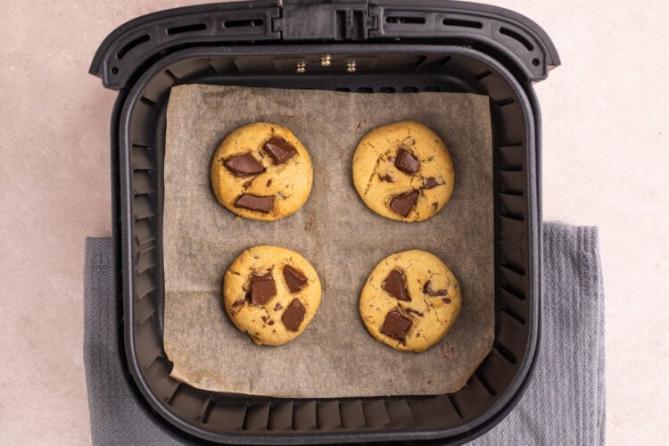 Overhead view of air fryer chocolate chip cookies on parchment paper in an air fryer basket.