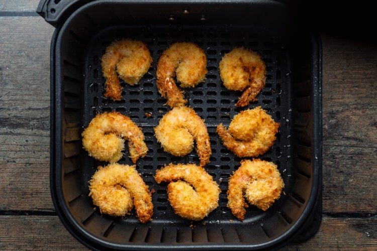 Overhead view of air fried shrimp in an air fryer basket.