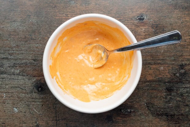 Overhead view of sriracha mayo in a bowl with a spoon.