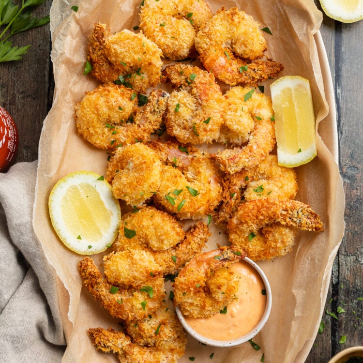 Overhead view of a platter of air fryer fried shrimp with sriracha mayo and lemon coins.