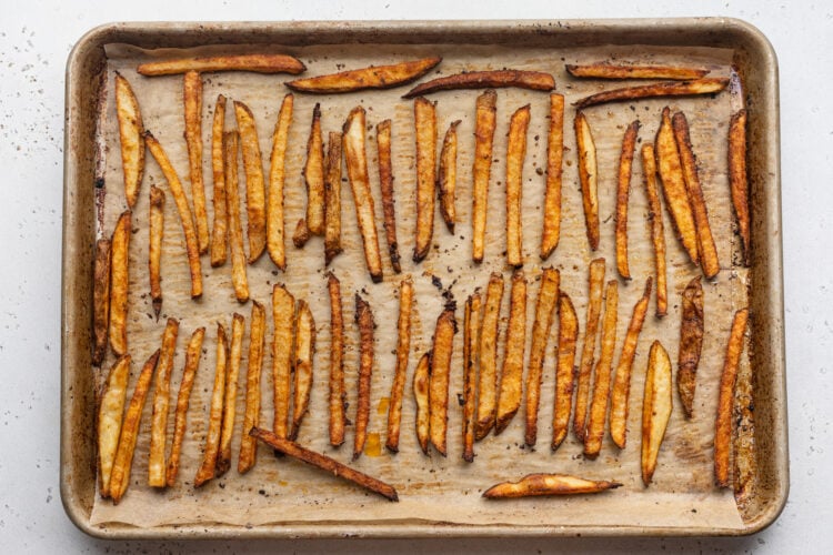 Overhead view of seasoned cajun fries on a baking sheet lined with parchment paper.