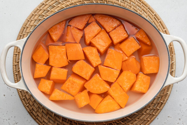 Overhead view of raw, peeled, cubed sweet potatoes in a large pot.