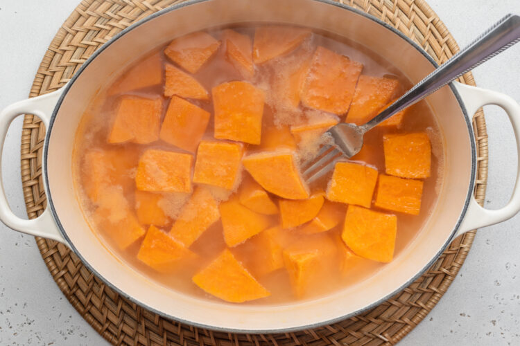 Overhead view of boiling, peeled, cubed sweet potatoes in a large pot.