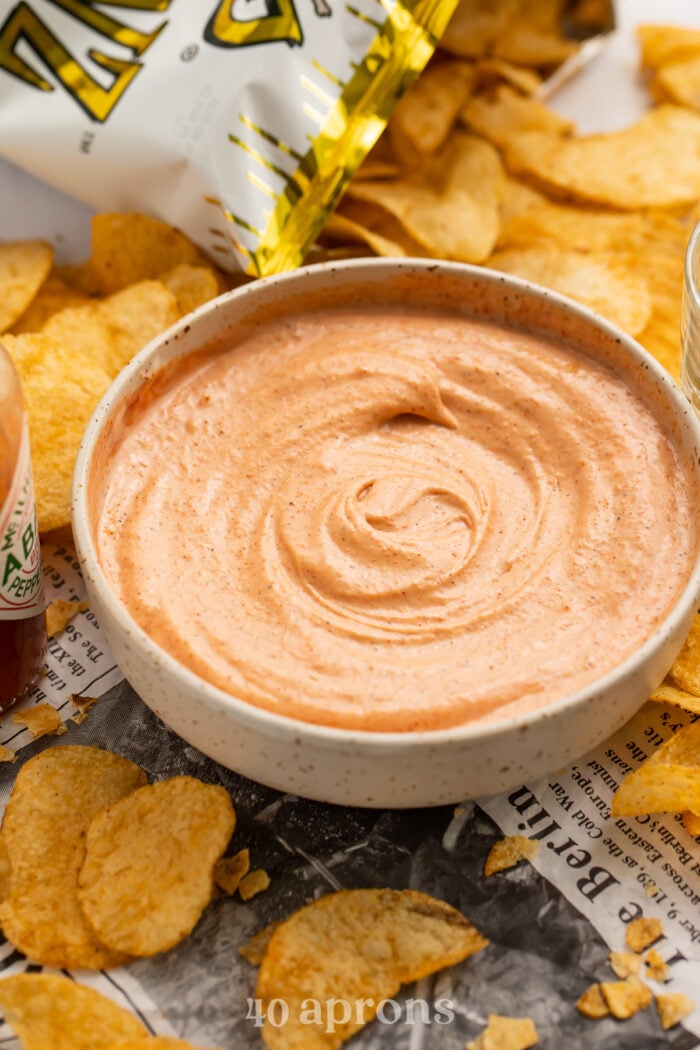 Side view of a bowl of cajun sauce surrounded by Zapp's potato chips.