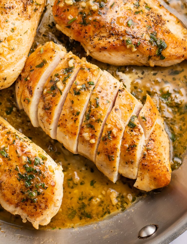Overhead view of a garlic butter chicken breast sliced diagonally into strips on a skillet.