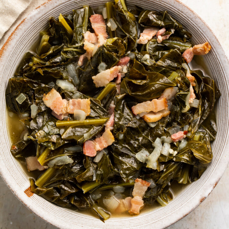 Overhead view of a white bowl of Instant Pot collard greens with bacon on a neutral tabletop.