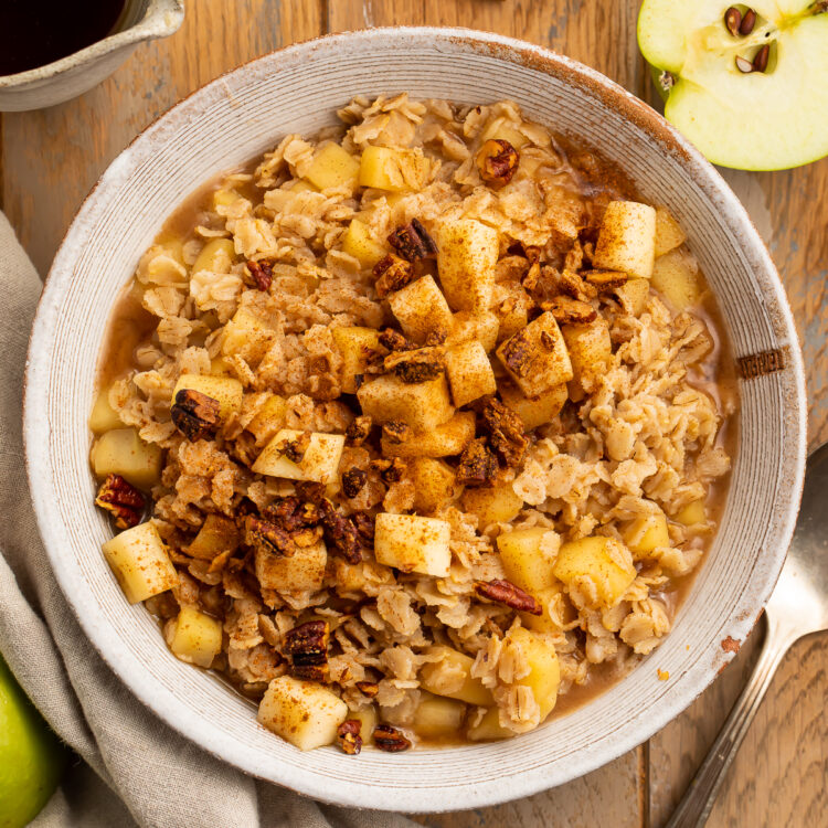 Overhead view of a large bowl of apple cinnamon oatmeal topped with brown sugar and cinnamon on a wooden table.