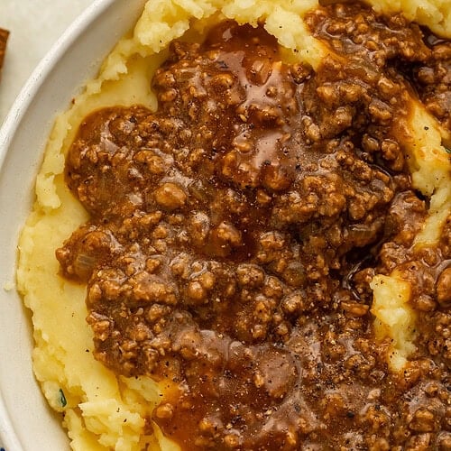 Ground beef in gravy over a bowl of mashed potatoes.