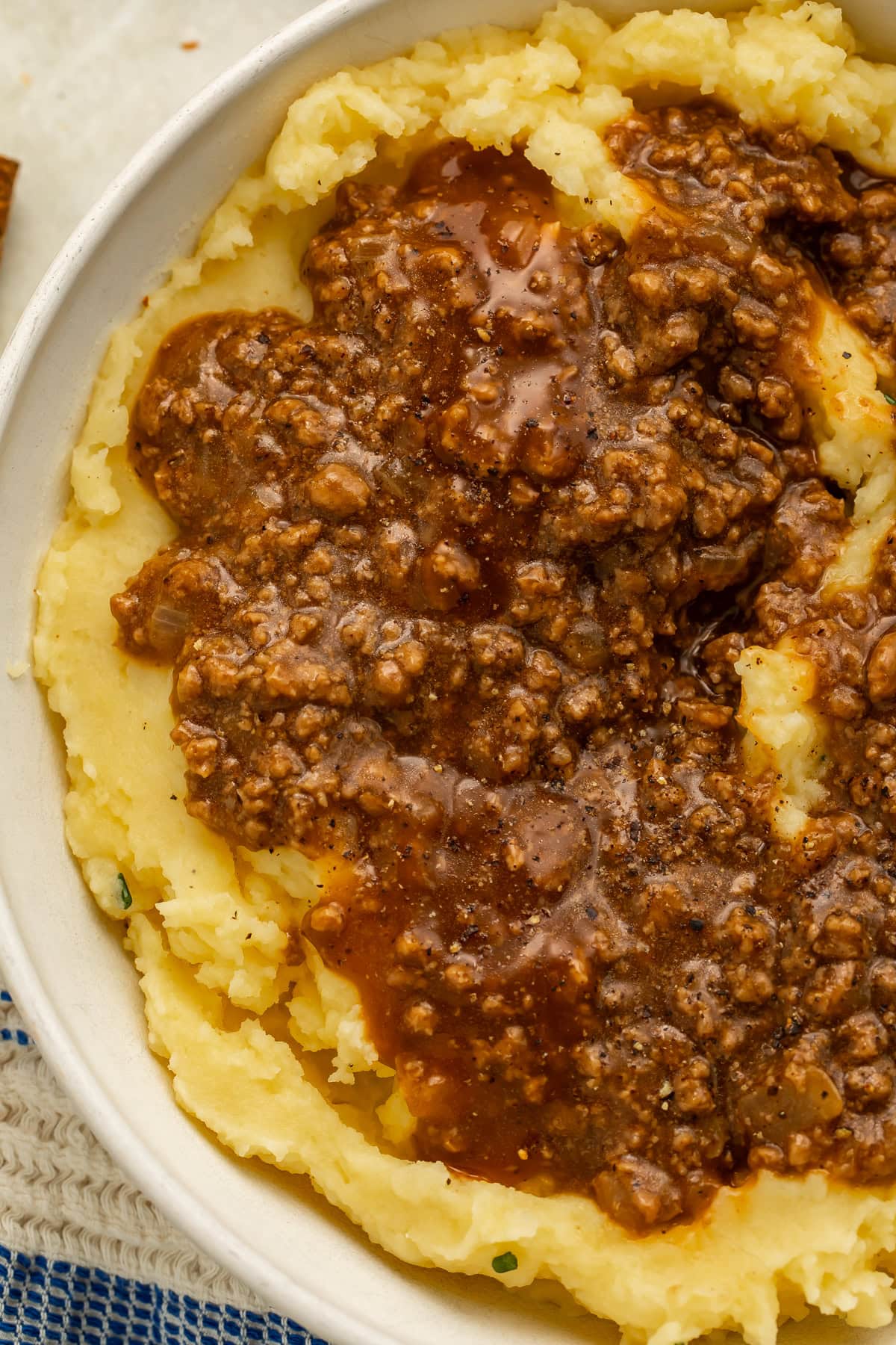 Ground beef in gravy over a bowl of mashed potatoes.
