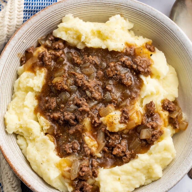 Overhead view of a bowl of ground beef and gravy on top of fluffy, creamy mashed potatoes.