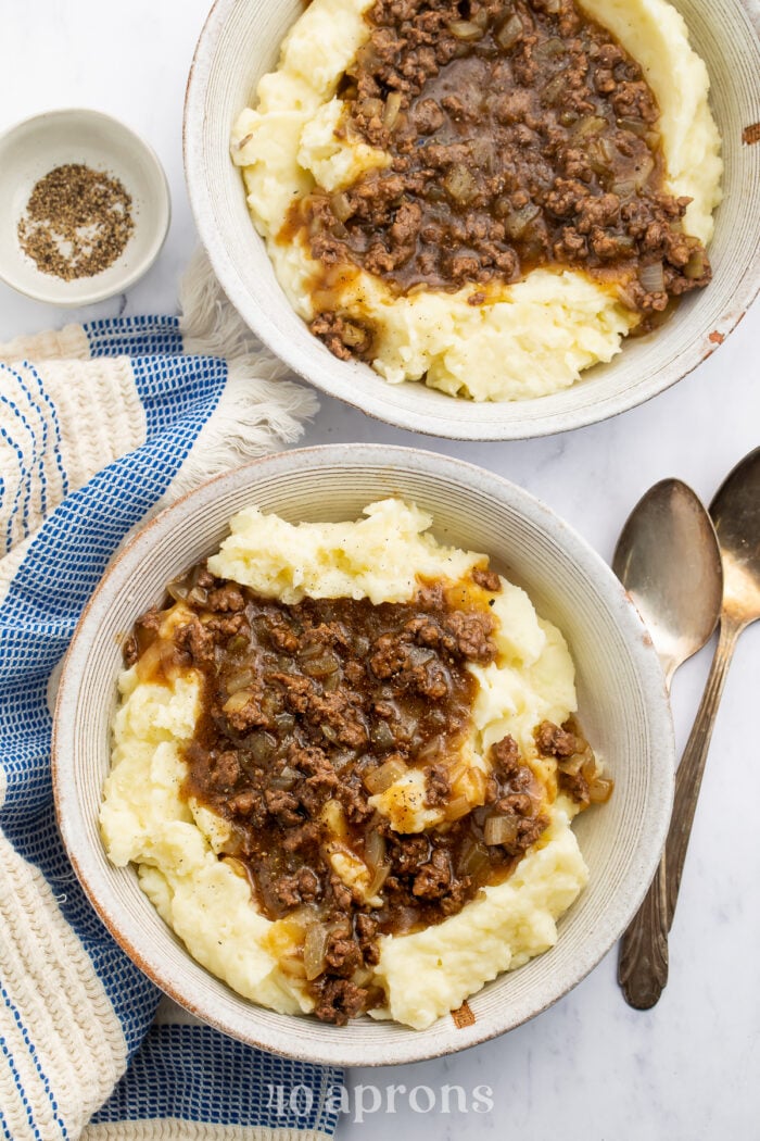 Zoomed out overhead view of a bowl of ground beef and gravy on top of fluffy, creamy mashed potatoes.