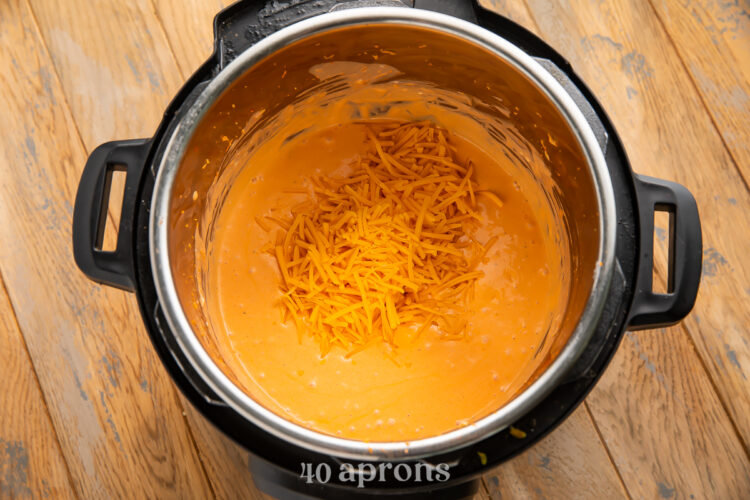 Overhead view of shredded cheddar cheese and other buffalo dip ingredients in an Instant Pot.