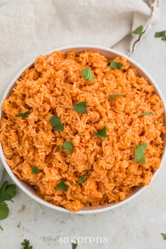 Overhead view of a large white bowl filled with orange Instant Pot Mexican rice and garnished with cilantro.