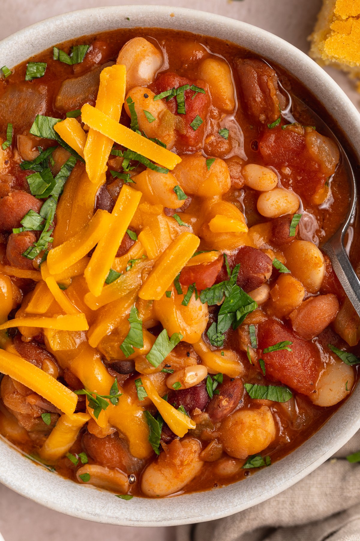 Close-up view of a bowl of 15-bean soup topped with shredded cheddar cheese.