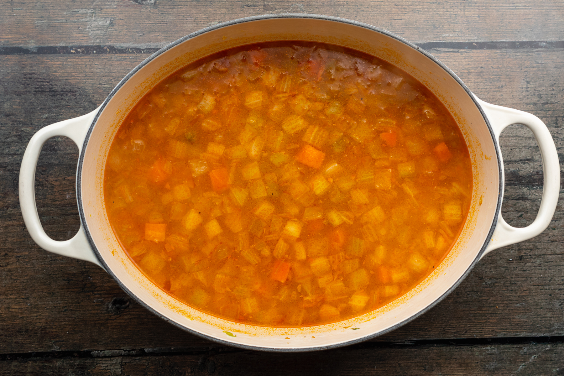 Cook making buffalo and vegetable soup in a large metal st…