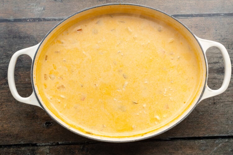 Overhead view of buffalo chicken soup in a large soup pot on a wooden table.