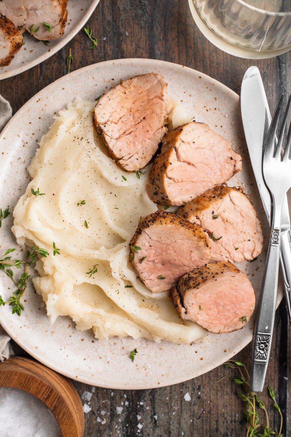 Overhead view of sous vide pork tenderloin sliced and plated with fluffy mashed potatoes on a wooden table.