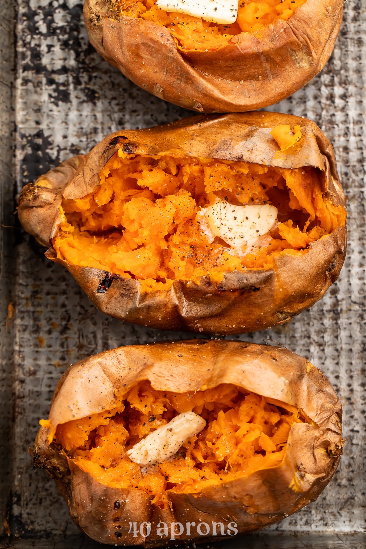 Overhead view of a vertical row of cut-open sweet potatoes on a sheet of parchment paper.