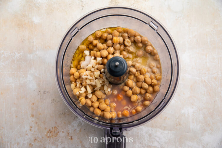 Overhead view of all buffalo hummus ingredients in a food processor bowl (uncovered) before processing.