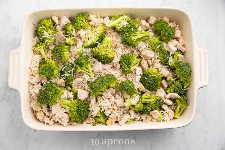 Overhead view of chicken, rice, and broccoli in a large white rectangular casserole dish.
