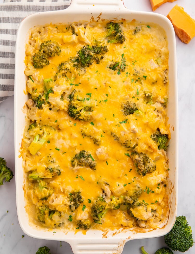 Overhead view of a white rectangular casserole dish full of cheesy chicken, broccoli, and rice.