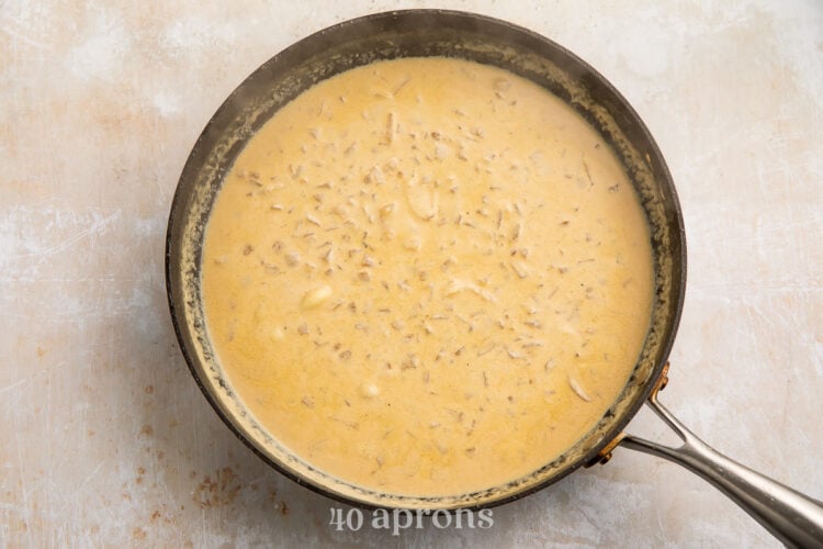 Overhead view of creamy garlic sauce for creamy garlic chicken in a large silver skillet on a white countertop.