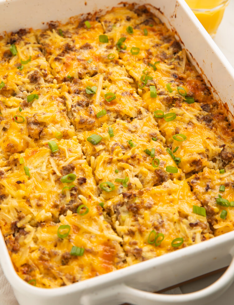 Angled photo of a rectangular white casserole dish with a fully-baked gluten free breakfast casserole cut into 12 squares.