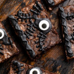 Close-up of one Hocus Pocus spellbook brownie out of 5 on a wooden tray surrounded by Halloween imagery.