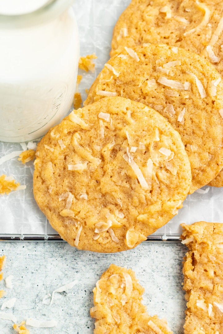 Overhead view of coconut cookies on a table next to a glass of coconut milk.