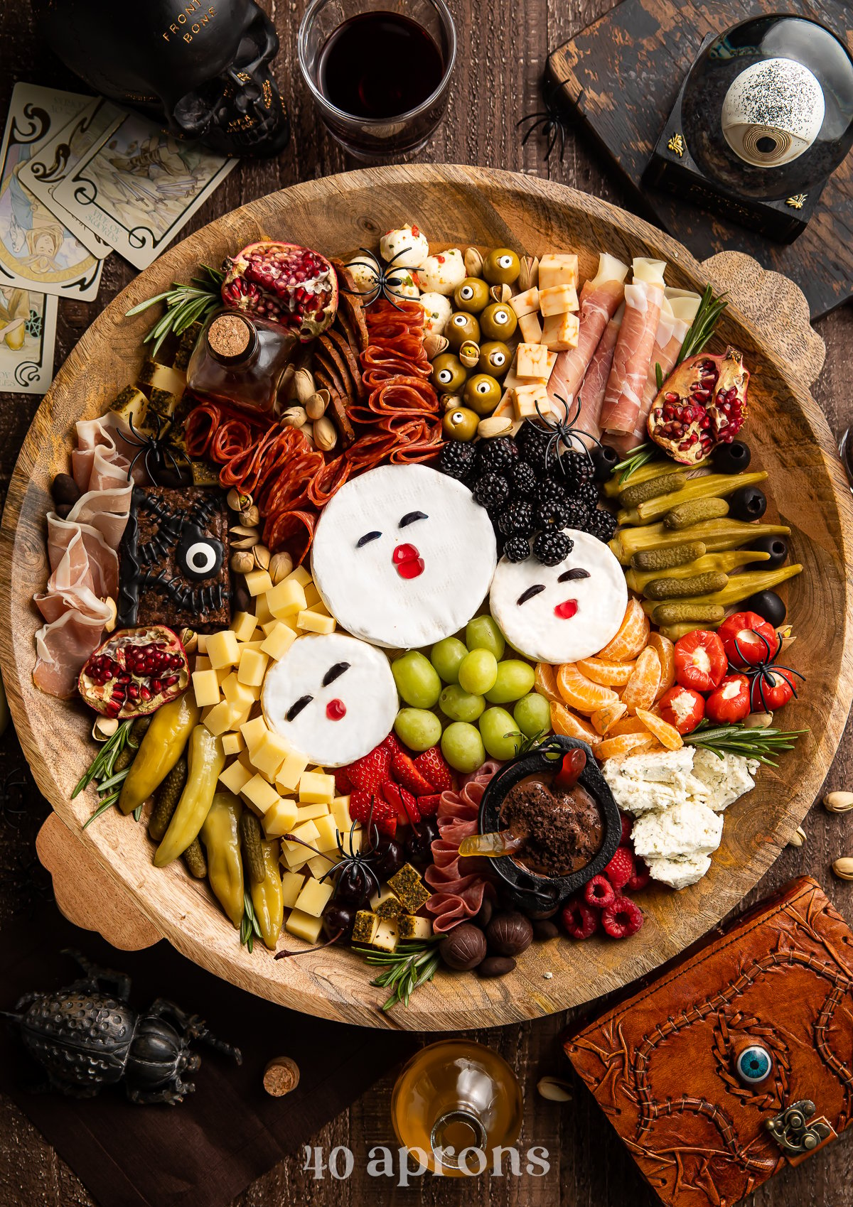 Overhead view of a Hocus Pocus themed charcuterie board with brie, fruit, cornichon, stuffed red peppers, marinated mozzarella, and other spooky snacks.