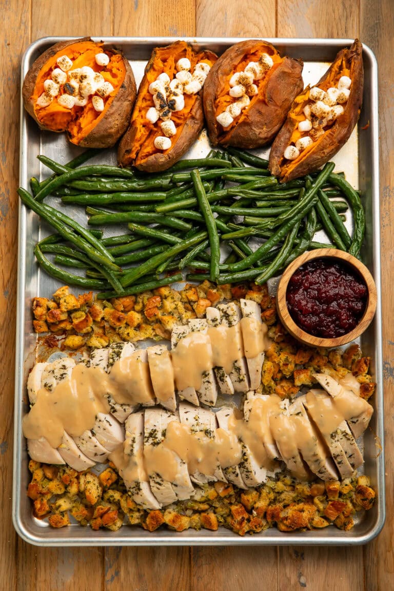 Sheet pan holiday meal with turkey, stuffing , green beans, marshmallow sweet potatoes and cranberry sauce.