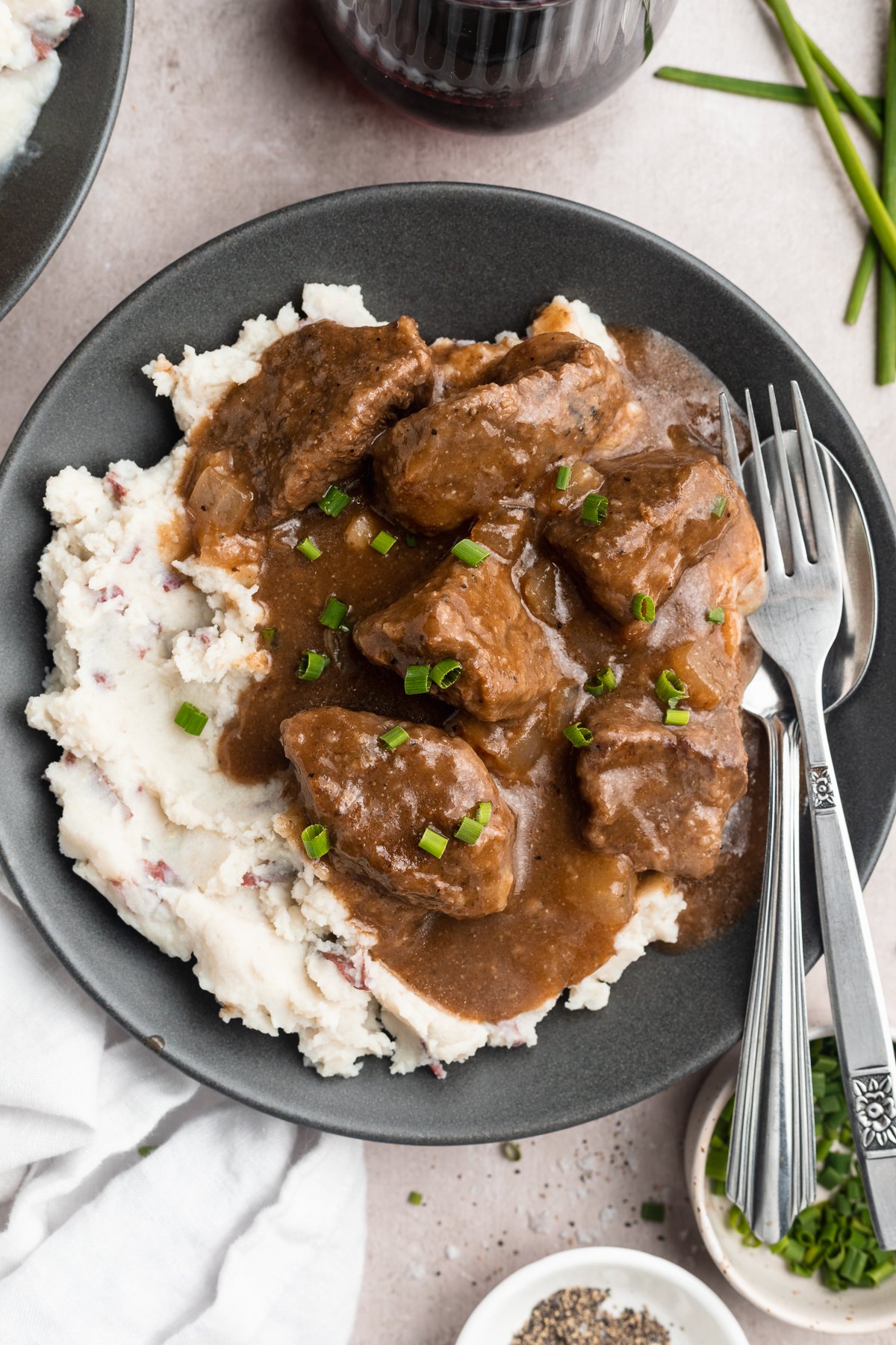 Overhead view of beef tips and gravy plated with white rice on a dark shallow bowl.